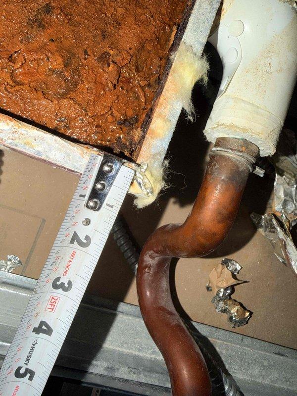 Performed indoor air quality assessment and HVAC system evaluation. Cut drywall access points to obtain precise measurements for drip pan replacement, documented motor and actuator specifications for equipment ordering. Protected work area with plastic sheeting and painter's tape to contain debris during ceiling access work, photographed existing plumbing infrastructure and corroded copper piping for documentation purposes.