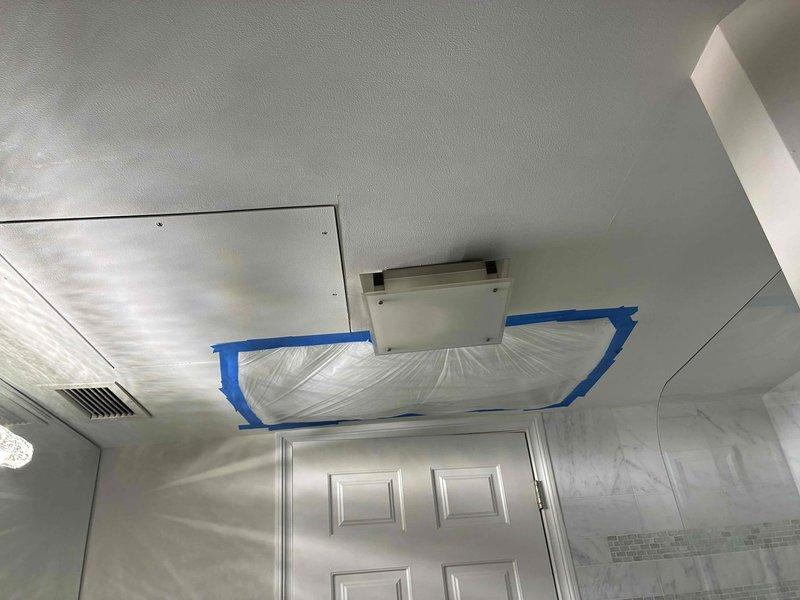 Performed indoor air quality assessment and HVAC system evaluation. Cut drywall access points to obtain precise measurements for drip pan replacement, documented motor and actuator specifications for equipment ordering. Protected work area with plastic sheeting and painter's tape to contain debris during ceiling access work, photographed existing plumbing infrastructure and corroded copper piping for documentation purposes.