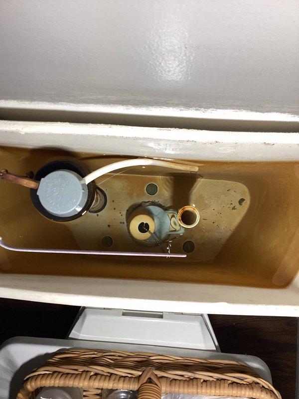 Completed comprehensive plumbing inspection with primary focus on toilet and bathroom faucet concerns. Upon inspection of the toilet tank, identified significant water discoloration with brownish rust-colored tinting throughout, indicating mineral deposits and potential aging pipe issues. Documented internal tank components including fill valve assembly with float mechanism and flush valve system, both showing signs of mineral buildup and staining on interior ceramic surfaces. The discolored water condition suggests possible corrosion in supply lines or water heater sediment transfer requiring further investigation and treatment.