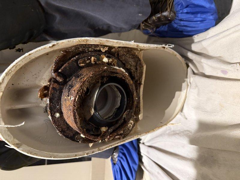 Responded to service callback for toilet replacement. Upon inspection, discovered severely corroded internal components within the existing toilet's flush mechanism, with extensive rust and oxidation damage to the metal housing and pump casing. Removed the failed toilet and existing floor flange, which exhibited significant water damage and deterioration with brown staining around the perimeter indicating long-term moisture intrusion. Installed new toilet flange assembly with proper sealing to prevent future water damage to the tile flooring. Completed installation of replacement toilet unit and verified proper operation and seal integrity. Documented conditions with photographs showing the extent of corrosion damage and the compromised floor flange prior to replacement.