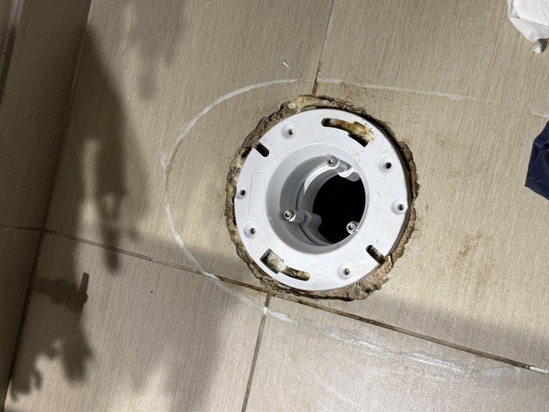 Responded to service callback for toilet replacement. Upon inspection, discovered severely corroded internal components within the existing toilet's flush mechanism, with extensive rust and oxidation damage to the metal housing and pump casing. Removed the failed toilet and existing floor flange, which exhibited significant water damage and deterioration with brown staining around the perimeter indicating long-term moisture intrusion. Installed new toilet flange assembly with proper sealing to prevent future water damage to the tile flooring. Completed installation of replacement toilet unit and verified proper operation and seal integrity. Documented conditions with photographs showing the extent of corrosion damage and the compromised floor flange prior to replacement.