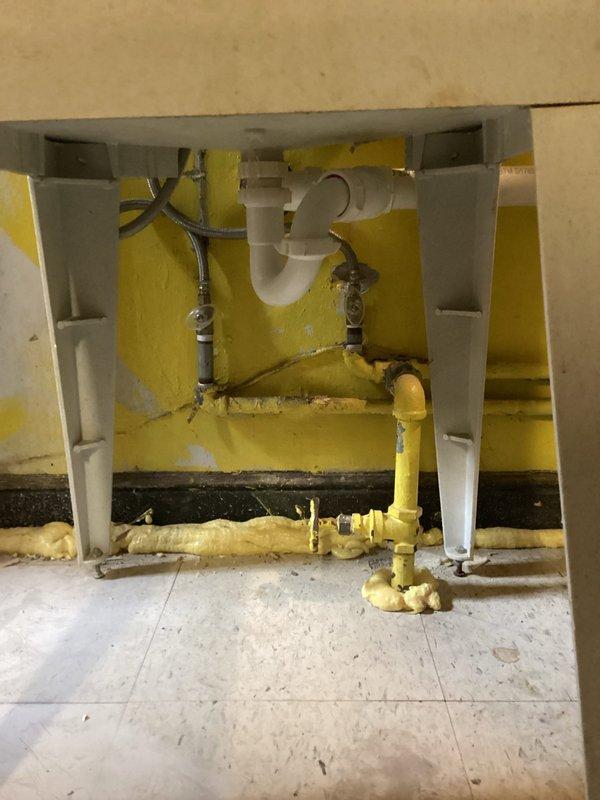 Completed inspection and estimate for bathroom vanity replacement in active renovation area with significant floor damage and exposed plumbing infrastructure. Assessment confirmed need for licensed plumber to properly disconnect existing supply lines, remove current fixtures, install new vanity cabinet, and reconnect water supply and drain assembly including P-trap configuration. Documented extensive tile damage, exposed substrate, yellow foam insulation application, and partially installed cabinetry requiring professional plumbing connections to meet code requirements.