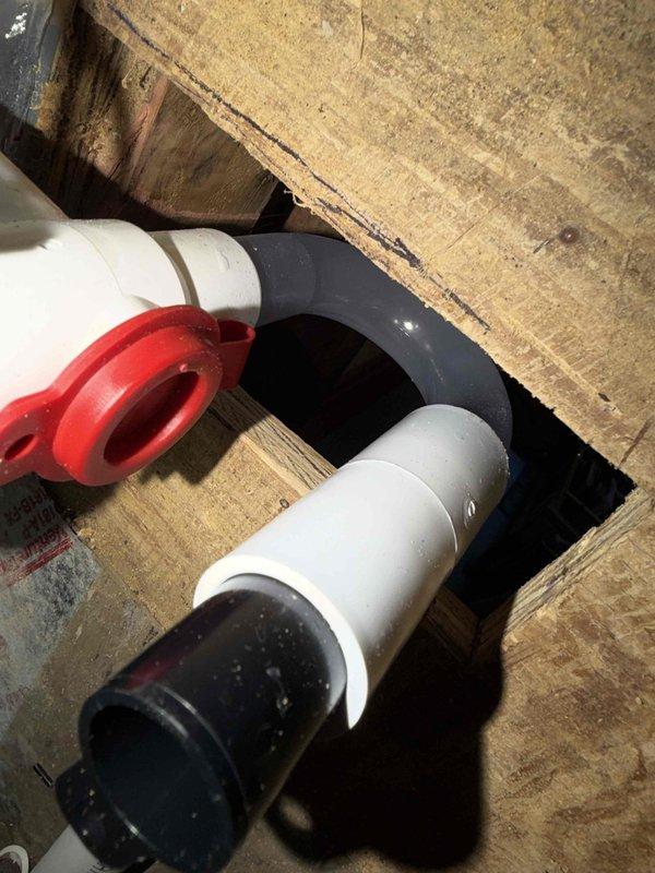 Returned to complete installation of EZ Trap condensate drain assembly using oscillating tool to modify existing drain line configuration. Successfully integrated new trap fitting with red coupling connector into PVC drain system between floor joists, ensuring proper condensate drainage and air seal. Verified all electrical connections at control board terminal block remained secure and system operational upon completion.