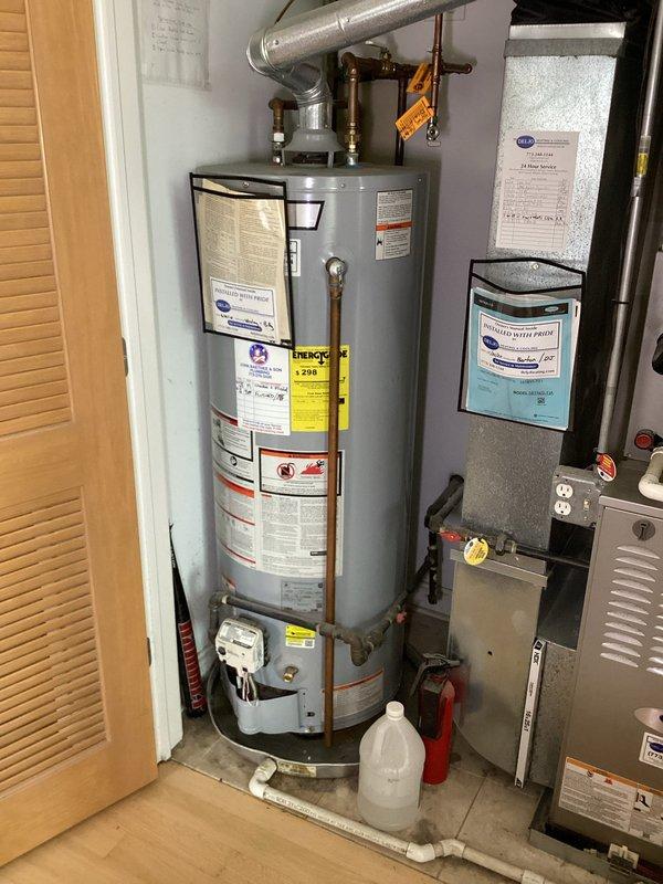 Responded to no hot water complaint and performed diagnostic evaluation of tanked water heater system. Upon inspection, identified standard residential gas water heater installation with copper supply lines, brass shut-off valves with red and white handle indicators, and proper drain pan configuration. Verified all plumbing connections at inlet and outlet ports, including compression fittings and brass coupling nuts. Examined water heater for proper venting through metallic ductwork and confirmed unit specifications via manufacturer labels and energy guide information. Assessed condition of copper piping showing normal patina oxidation consistent with system age. Documented complete installation including safety valves, temperature and pressure relief components, and gas supply connections. Coordinated access with tenant for appointment window and completed thorough visual inspection of water heater closet including adjacent HVAC equipment. Photographed installation details for service