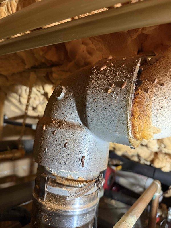 # HVAC Exhaust Repair

Returned to address leaking CPVC exhaust pipe penetrating through roof assembly. Upon inspection, discovered extensive corrosion and deterioration on metal elbow fitting connected to exhaust system. Component exhibited heavy rust, oxidation, and surface pitting with visible moisture accumulation and condensation buildup indicating active leak condition. Metal hose clamp securing connection showed signs of failure to maintain proper seal.

Removed corroded elbow fitting and replaced with new component. Installed proper sealing materials and secured all connections with appropriate clamps to manufacturer specifications. Verified exhaust system integrity and confirmed no additional moisture intrusion at roof penetration point. System tested and operational with no leaks detected upon completion.