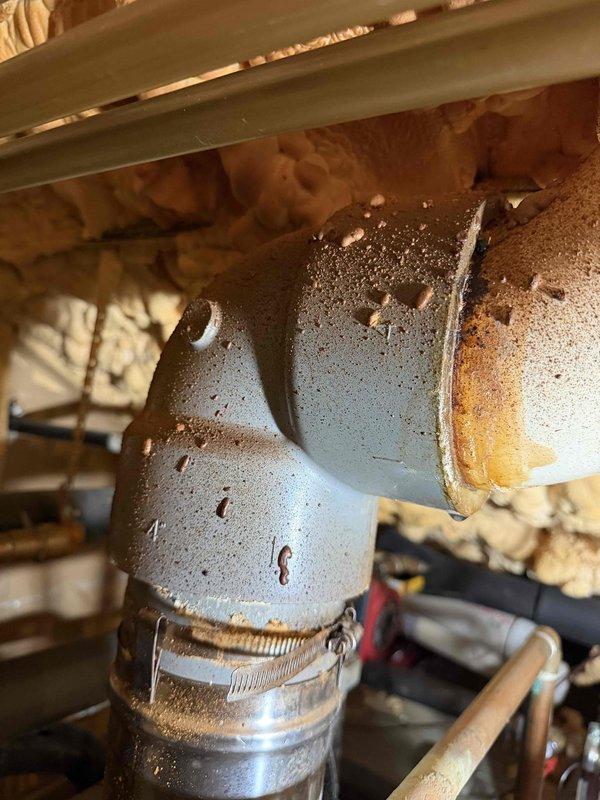 # HVAC Exhaust Repair

Returned to address leaking CPVC exhaust pipe penetrating through roof assembly. Upon inspection, discovered extensive corrosion and deterioration on metal elbow fitting connected to exhaust system. Component exhibited heavy rust, oxidation, and surface pitting with visible moisture accumulation and condensation buildup indicating active leak condition. Metal hose clamp securing connection showed signs of failure to maintain proper seal.

Removed corroded elbow fitting and replaced with new component. Installed proper sealing materials and secured all connections with appropriate clamps to manufacturer specifications. Verified exhaust system integrity and confirmed no additional moisture intrusion at roof penetration point. System tested and operational with no leaks detected upon completion.