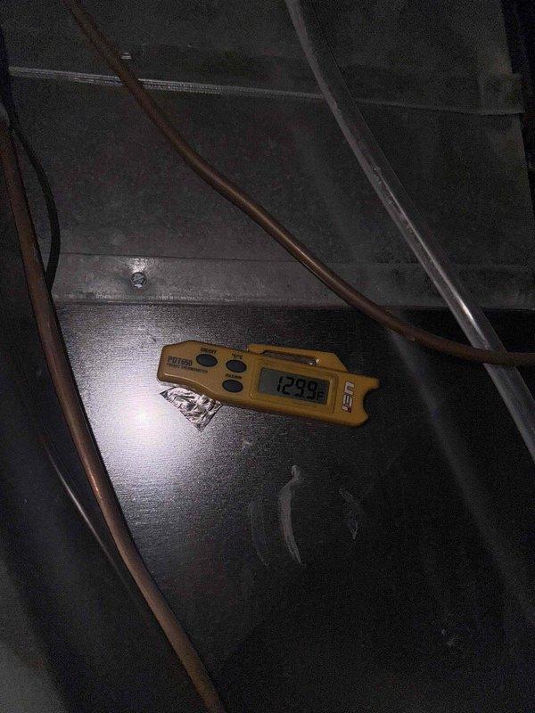 Completed return visit to replace thermostat. Removed existing thermostat from wall-mounted base plate and installed new unit, verifying proper wire connections at terminal screws including power, heating, cooling, and common wires. Tested system operation at air handler using diagnostic equipment to confirm proper communication between new thermostat and HVAC equipment, with temperature readings indicating normal system function at 129.9°F.
