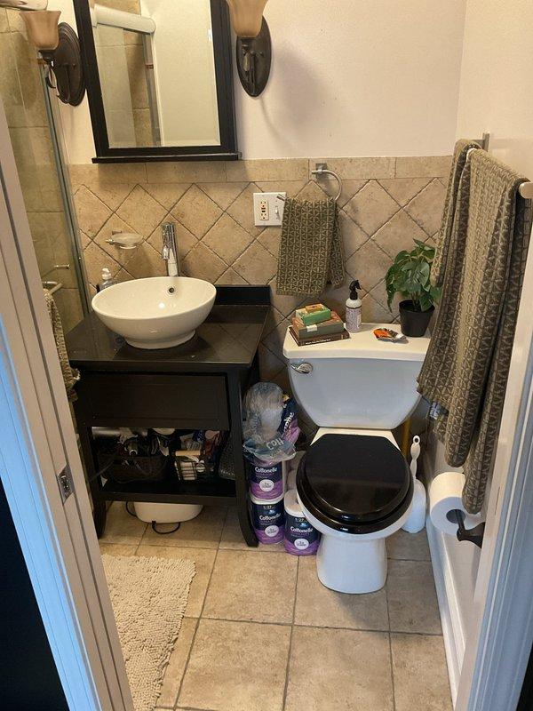 Conducted a comprehensive two-hour leak search investigation in a residential bathroom and adjacent kitchen area. Performed thorough visual inspection of all plumbing fixtures, including vessel sink, toilet, and cabinet areas, to identify potential water intrusion sources. Documented findings with photographic evidence showing cabinet interiors, wall conditions, and bathroom fixtures for repair assessment and future reference.