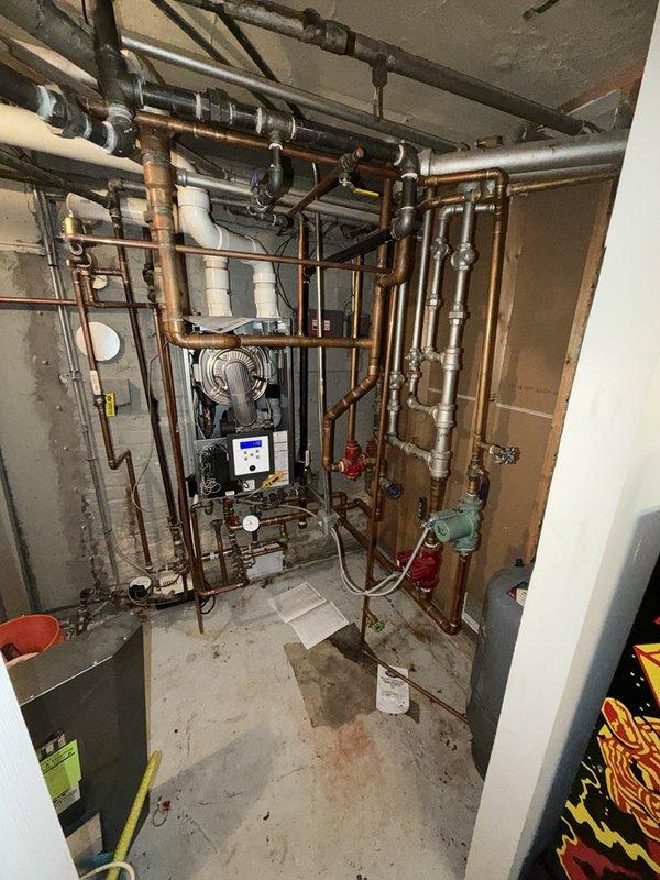 Responded to service call for NTI tankless water heater experiencing consistent water pressure loss. Upon inspection of the mechanical room installation, evaluated the complete plumbing system including copper supply lines, manifold configuration, and associated shut-off valves. Examined the tankless unit's digital control interface and verified operational parameters. Inspected all pipe connections, fittings, and isolation valves throughout the system for potential pressure restrictions or flow impediments. Assessed the condition of aging copper piping showing corrosion and mineral deposits that could contribute to pressure reduction. Checked valve operation and flow characteristics at multiple points in the distribution system. Documented existing conditions with photographic evidence showing the complete mechanical installation and specific areas of concern. Identified potential causes of pressure loss including sediment buildup, valve restrictions, or internal heat exchanger scalin