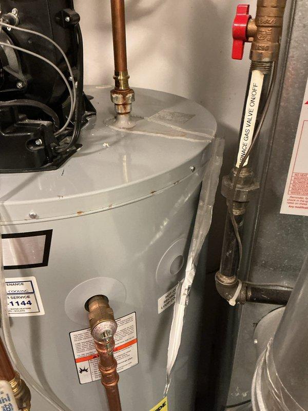 Responded to service call for leaking pipe at top of residential water heater. Upon inspection, identified active leak at copper pipe connection above the unit. Assessed circulation pump assembly and associated plumbing connections for proper installation and potential sources of the leak. Documented conditions with photographs showing the water heater installation, copper piping configuration, shut-off valves, and circulation pump assembly in the mechanical room.