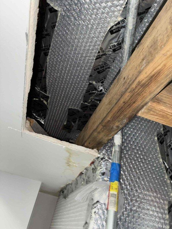 Completed insulation of accessible ductwork and plenum in commercial space using reflective bubble wrap insulation material. All exposed ductwork sections and plenum chamber were wrapped with metallic insulation to improve thermal efficiency and prevent condensation buildup. Work was performed in ceiling cavity with coordination of tenant access.