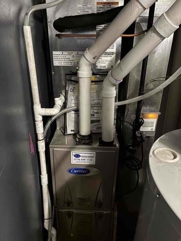 Completed installation of new condenser unit and evaporator coil system. Two-technician crew successfully removed existing outdoor condenser and indoor coil assembly, installed replacement Carrier-compatible equipment, established proper refrigerant lines with braided connections, and verified all mechanical connections and ductwork integration. System tested and operational with proper venting and drainage confirmed.