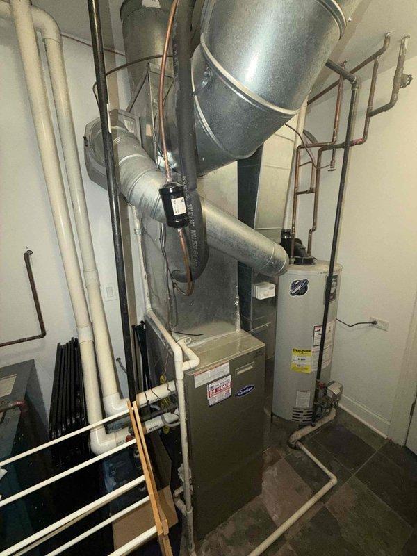 Conducted on-site evaluation for complete HVAC system replacement. Existing equipment includes a 21-year-old furnace located in basement mechanical room and a 21-year-old air conditioning condenser unit positioned on exterior deck. Documented current system configuration through photographic assessment, including measurements of outdoor condenser unit dimensions and evaluation of indoor furnace installation with associated ductwork, expansion tank, and plumbing connections. Assessed condition of aged equipment showing normal wear and surface deterioration consistent with two decades of operation. Provided replacement estimate for new heating and cooling system to address equipment that has exceeded typical service life expectancy.
