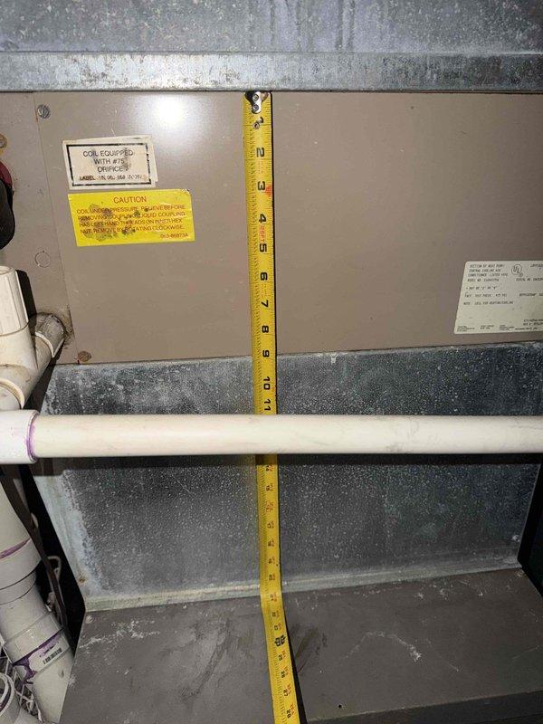 Completed comprehensive estimate for full HVAC system replacement in residential basement mechanical room. Documented existing air handler unit with coil assembly mounted against concrete block wall, measuring clearances and dimensional requirements for new equipment installation. Photographed current ductwork configuration including main supply trunk line and branch connections, noting accumulated dust and age-related deterioration. Assessed electrical service panel and existing control wiring mounted to foundation wall. Evaluated copper refrigerant line routing and condensate drainage piping. Measured available working space around existing equipment to ensure compliance with manufacturer specifications and local code requirements for new system installation. Documented structural floor joists and clearance heights for proper equipment sizing recommendations.