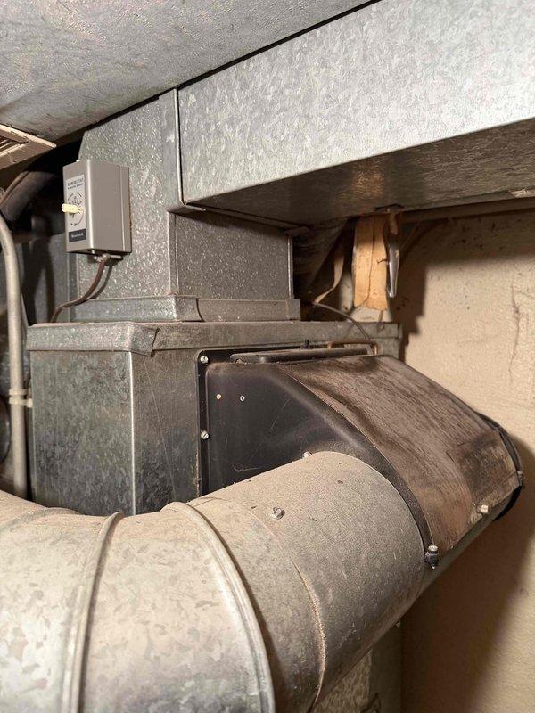 Completed comprehensive estimate for full HVAC system replacement in residential basement mechanical room. Documented existing air handler unit with coil assembly mounted against concrete block wall, measuring clearances and dimensional requirements for new equipment installation. Photographed current ductwork configuration including main supply trunk line and branch connections, noting accumulated dust and age-related deterioration. Assessed electrical service panel and existing control wiring mounted to foundation wall. Evaluated copper refrigerant line routing and condensate drainage piping. Measured available working space around existing equipment to ensure compliance with manufacturer specifications and local code requirements for new system installation. Documented structural floor joists and clearance heights for proper equipment sizing recommendations.