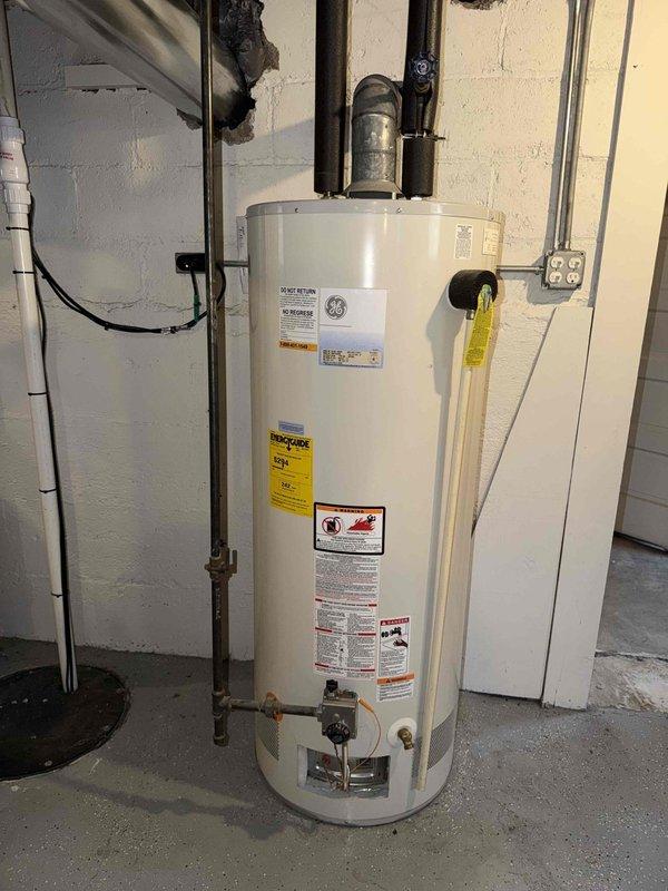 Responded to service call for non-operational water heater following recent service visit. Upon arrival, performed comprehensive inspection of GE residential electric water heater unit installed in basement utility area. Verified all plumbing connections, pressure relief valve operation, and electrical supply to unit. Conducted diagnostic measurements of equipment clearances and mounting components to ensure proper installation specifications were met. Documented existing conditions with photographic evidence showing water heater positioning, pipe connections, and associated mechanical infrastructure for service records.