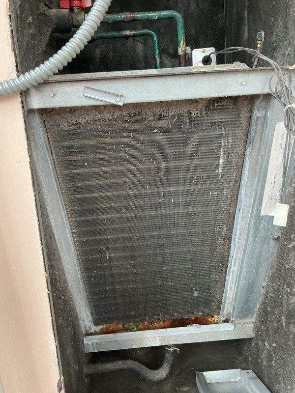 Returned to property to complete evaporator coil cleaning as part of building wellness check follow-up. Upon arrival, found extensive ice and frost buildup covering the entire evaporator coil assembly, with heavy accumulation on fins and icicle-like formations indicating active freezing condition. Addressed the frozen coil issue, performed thorough cleaning of the evaporator coil to remove dirt, dust, and debris accumulation from fin surfaces. Cleaned corroded areas at base of unit and ensured proper system operation upon completion.