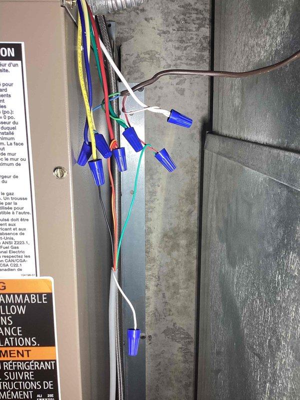Responded to no cooling complaint on 9-year-old MagicPak unit installed in July. Diagnosed intermittent power loss affecting condenser operation and wet switch sensor, along with "no power to R wire" error at Nest thermostat. Inspected electrical connections and wire terminations at unit, finding loose connections at low-voltage terminal block causing intermittent power interruptions. Secured all wire connections using proper wire nuts and verified continuity on R wire circuit to thermostat. Addressed standing water in condensate pan by clearing partial blockage in drain line and confirming proper wet switch operation. Cycled system through multiple cooling cycles to verify consistent power delivery to all components and confirmed condenser now running continuously without interruption. Thermostat displaying proper power status and unit operating normally at departure.