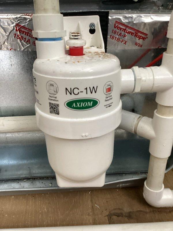 Responded to callback regarding water leak traces under PVC piping following previous maintenance visit. Inspected AXIOM NC-1W water treatment unit and associated PVC drainage system, finding minor moisture residue but no active leaking present. Verified all pipe connections and fittings are secure with proper sealing. Confirmed furnace access doors are properly closed, flush-mounted, and fully secured. Inspected and verified air filter is correctly installed with proper orientation and fitment. Documented equipment conditions with photos showing VentMaster system components and condensate drainage assembly with aggregate trap material. All systems operating within normal parameters with no immediate service needs identified.