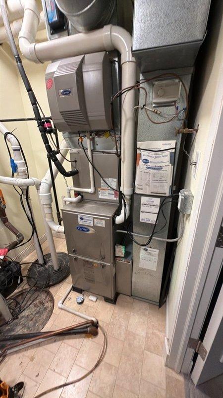 Completed comprehensive maintenance agreement service on two residential air conditioning systems. Performed thorough inspection of Carrier furnace, associated humidifier unit, and connected HVAC components in mechanical room. Verified proper operation of thermostat control system, which was maintaining setpoint at 65 degrees with current temperature reading of 69 degrees. Inspected all copper refrigerant lines, PVC drainage and ventilation piping, electrical conduits, and system connections for proper installation and functionality. Documented equipment conditions through photography for maintenance records.
