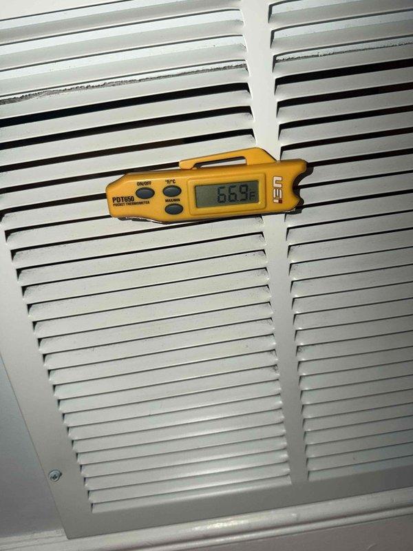Responded to service call for AC short cycling issue. Upon arrival, performed system diagnostics and measured return air temperature at 86.9°F using digital thermometer at ceiling grille. Identified short cycling condition and completed troubleshooting procedures to resolve cooling system malfunction.
