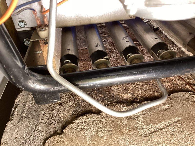 Completed scheduled maintenance agreement inspection on residential gas boiler system. Documented interior burner assembly showing moderate dust and debris accumulation on burner tubes, chamber surfaces, and surrounding components, with all structural elements remaining intact and functional. Inspected horizontally-mounted expansion tank installation and associated piping connections in utility area, verifying proper mounting and system configuration.