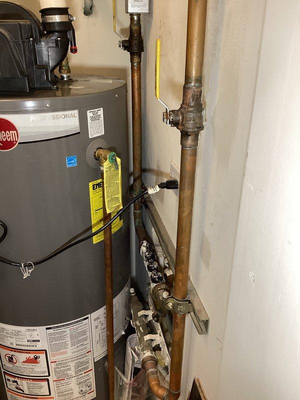 Responded to reported leak in utility area near water heater and furnace. Conducted comprehensive plumbing inspection of the premises as requested. Examined Rheem Professional series tanked water heater installation, including all associated copper supply lines, pressure relief valve, expansion tank, shutoff valves, and manifold connections. Inspected all visible plumbing components for signs of active leaks, moisture damage, or deterioration. Verified proper installation of safety devices and code-compliant fixtures. Assessed bathroom plumbing fixtures including wall-mounted sink, brass faucet assembly, P-trap drain configuration, and supply line connections. All plumbing systems evaluated for proper function and potential issues. Documented equipment condition and installation with photographs for service records.