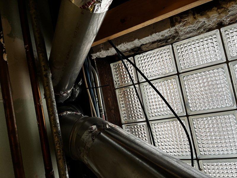 Conducted comprehensive evaluation of existing boiler system exceeding 10 years of service life. Unit currently operational but has demonstrated declining reliability over multiple heating seasons, prompting replacement assessment. Documented existing equipment configuration including basement installation with associated piping infrastructure and exterior venting components terminating through corrugated metal roof structure.