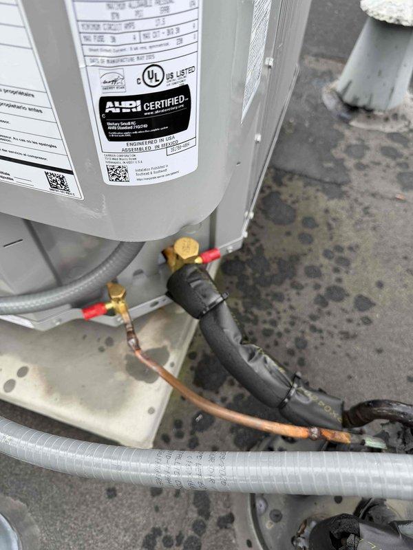 Completed install warranty inspection on rooftop condenser unit. Verified proper operation of newly installed system, confirmed refrigerant pressures reading 283 PSI on high side with appropriate temperature differential of 20 degrees. Inspected copper line set connections with insulation sleeves, service valves, and electrical conduit for proper installation standards. Unit operating within manufacturer specifications with all AHRI and UL certifications visible and intact.