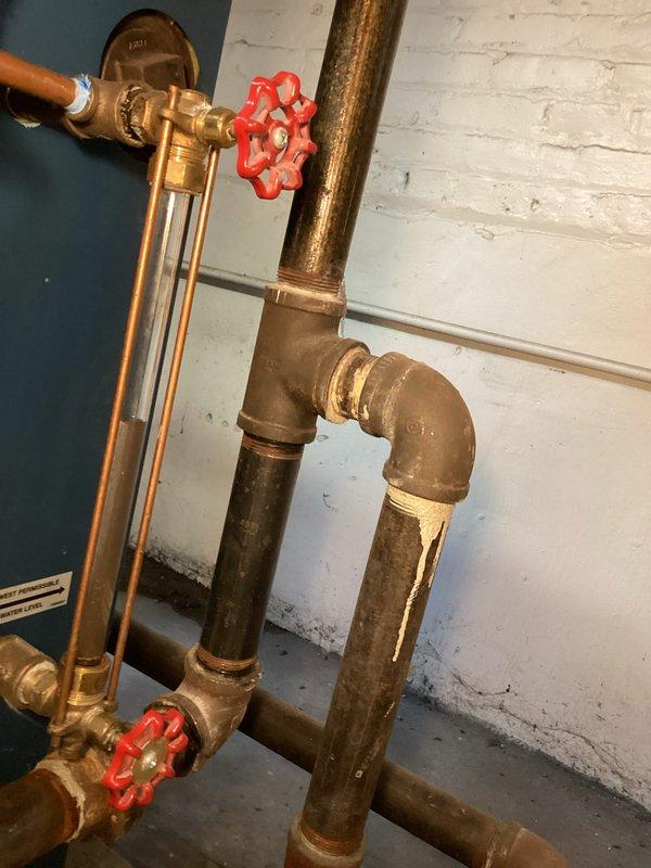 Completed annual maintenance agreement inspection on boiler system. Documented existing hydronic piping configuration including zone valves, pressure relief components, and copper supply lines showing normal patina development. Inspected burner assembly, noted aged insulation material on flue piping with visible deterioration, and verified all safety controls and limit switches operational.