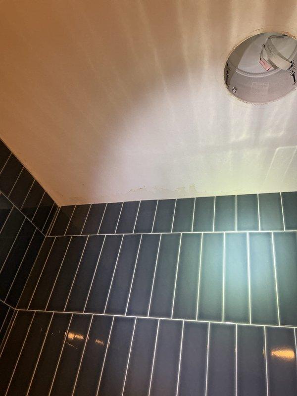 Responded to callback for water buildup from upstairs HVAC unit leaking into bathroom. Upon inspection, found evidence of ceiling water damage and staining above shower area near recessed lighting fixture. Investigated potential connection to previous maintenance performed on 9/2, documented conditions with photos showing extent of water intrusion and discoloration on bathroom ceiling adjacent to tiled shower enclosure.