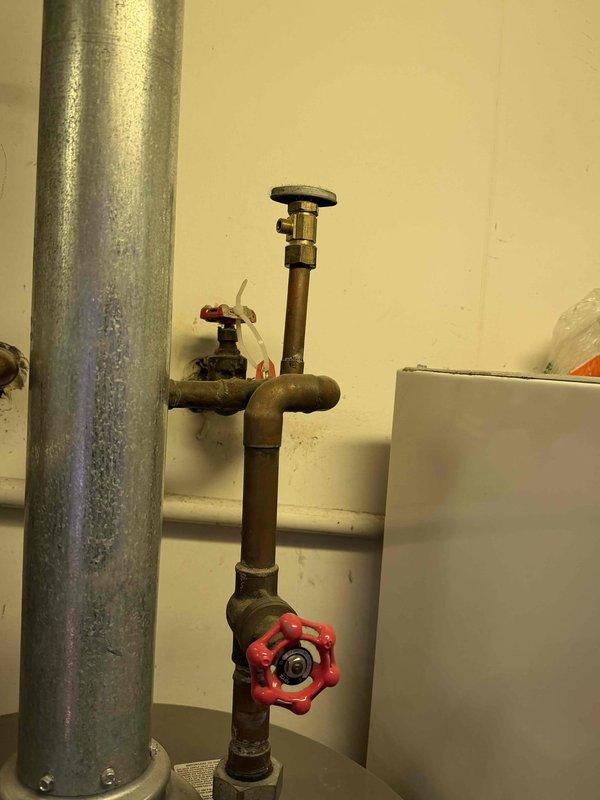Responded to reported water leak at tanked water heater installation. Upon inspection, identified leak originating from brass valve assembly on water supply line connected to Rheem water heater unit. Tightened compression fittings on vertical pipe assembly and verified all shut-off valves for proper sealing. Tested system under full pressure and confirmed leak was resolved with no further water discharge detected.