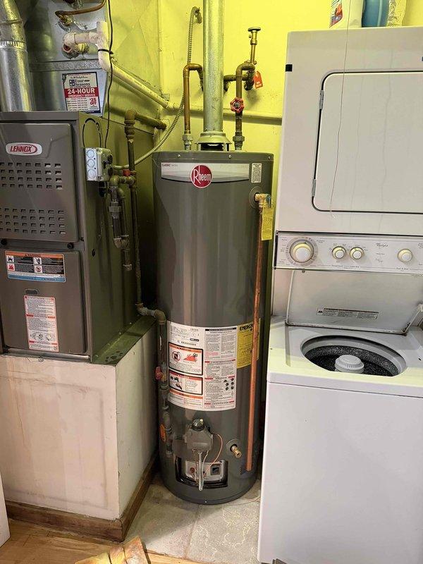 Responded to reported water leak at tanked water heater installation. Upon inspection, identified leak originating from brass valve assembly on water supply line connected to Rheem water heater unit. Tightened compression fittings on vertical pipe assembly and verified all shut-off valves for proper sealing. Tested system under full pressure and confirmed leak was resolved with no further water discharge detected.