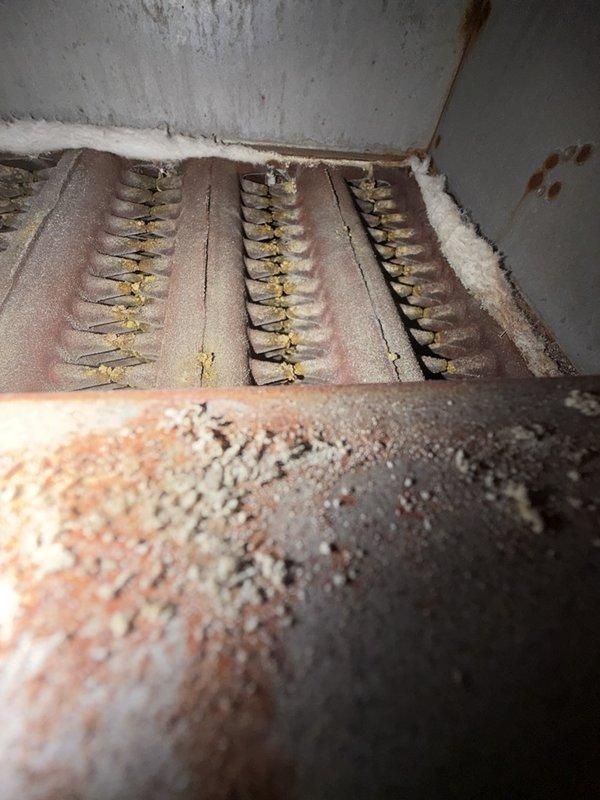 Completed comprehensive maintenance inspection on CC 1 boiler system under agreement terms. Documented system condition through photographs, revealing significant rust accumulation on ventilation ductwork connections, condensation throughout duct assembly indicating potential temperature differential issues, and visible corrosion on heating element terminals and connectors. Inspected internal heating components including terminal strips with brass connectors showing oxidation and dust buildup, examined insulation condition noting deterioration and contamination, and assessed overall system integrity for continued safe operation.