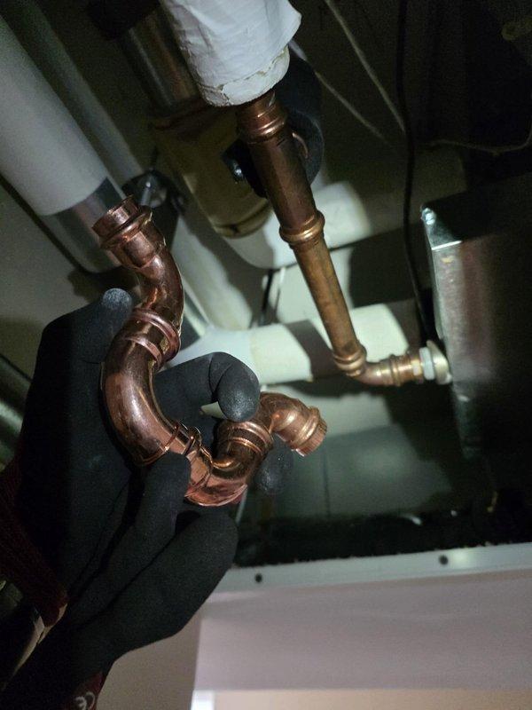 Installed drip pad in ceiling beneath HVAC unit to collect and manage condensate drainage. Performed copper pipe soldering and brazing work to connect plumbing components with proper fittings and joints, ensuring secure connections within the mechanical space. Documented installation with photos showing completed copper piping assembly and active soldering process.