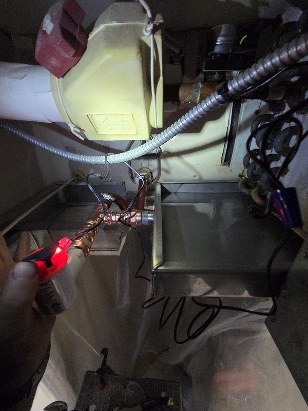 Installed drip pad in ceiling beneath HVAC unit to collect and manage condensate drainage. Performed copper pipe soldering and brazing work to connect plumbing components with proper fittings and joints, ensuring secure connections within the mechanical space. Documented installation with photos showing completed copper piping assembly and active soldering process.