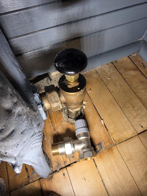 Returned to site with correct replacement valve and successfully replaced faulty radiator valve on exterior hydronic heating system. The new brass valve with black handle was installed on wooden deck area against exterior wall, completing the heating system repair. Payment was collected upon completion of the work.