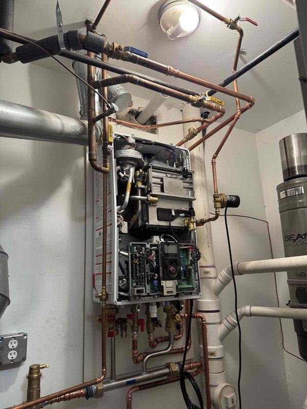 Completed full boiler replacement with wall-mounted tankless unit installation over two-day period with two-person crew. Removed existing boiler system and installed new tankless water heater with complete copper piping reconfiguration, including supply and return manifolds with multiple shut-off valves and brass fittings. Connected unit to existing BEAX expansion tank, installed circulation pump, pressure relief valve, and configured all electrical connections and control boards. Routed exhaust venting system and completed all plumbing connections to ensure proper operation of the heating system.