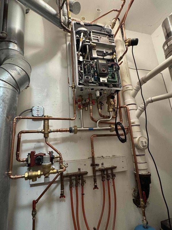 Completed full boiler replacement with wall-mounted tankless unit installation over two-day period with two-person crew. Removed existing boiler system and installed new tankless water heater with complete copper piping reconfiguration, including supply and return manifolds with multiple shut-off valves and brass fittings. Connected unit to existing BEAX expansion tank, installed circulation pump, pressure relief valve, and configured all electrical connections and control boards. Routed exhaust venting system and completed all plumbing connections to ensure proper operation of the heating system.