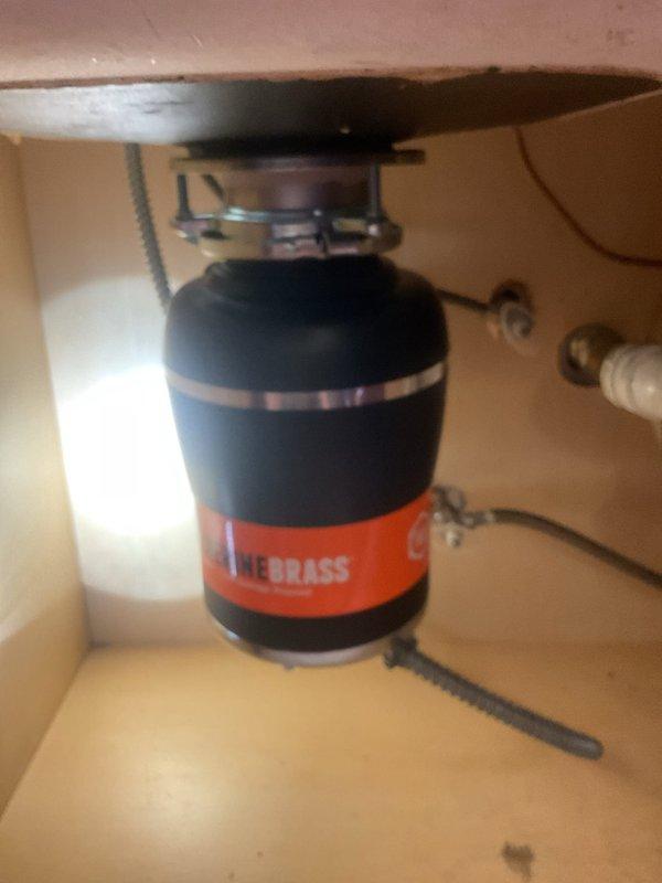 Responded to service call for leaking garbage disposal unit. Upon inspection, identified active water leak from Badger 100 model disposal that had previously experienced jamming issues. Assessed mounting assembly, drain connections, and discharge plumbing for source of leak. Found compromised seal at sink flange connection point. Evaluated overall condition of disposal unit and determined extent of water damage to surrounding cabinet area. Documented existing installation configuration including PVC drain lines, dishwasher discharge connection, and electrical connections. Provided assessment of disposal condition and recommended repair options to address the ongoing leak issue that had been present for multiple days.