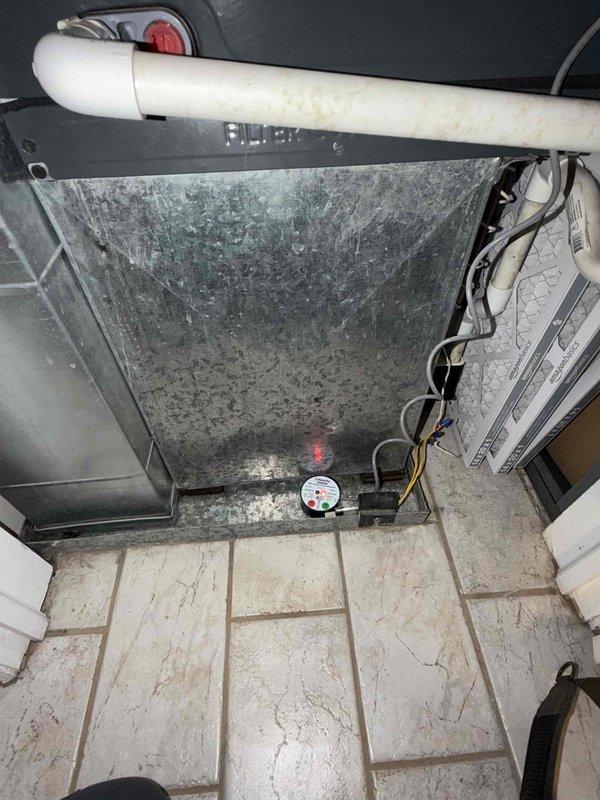 Responded to callback for wet switch showing red light indicator with moisture accumulation at base of unit. Upon arrival, inspected air handler and condensate management system, noting significant dust and debris buildup on equipment exterior. Documented existing conditions with photos showing wet switch status, PVC condensate drain line configuration, and overall system installation. Verified wet switch was recently installed and confirmed moisture presence at bottom of unit. Issue determined to be related to original concern and addressed under warranty provisions as no-charge callback.
