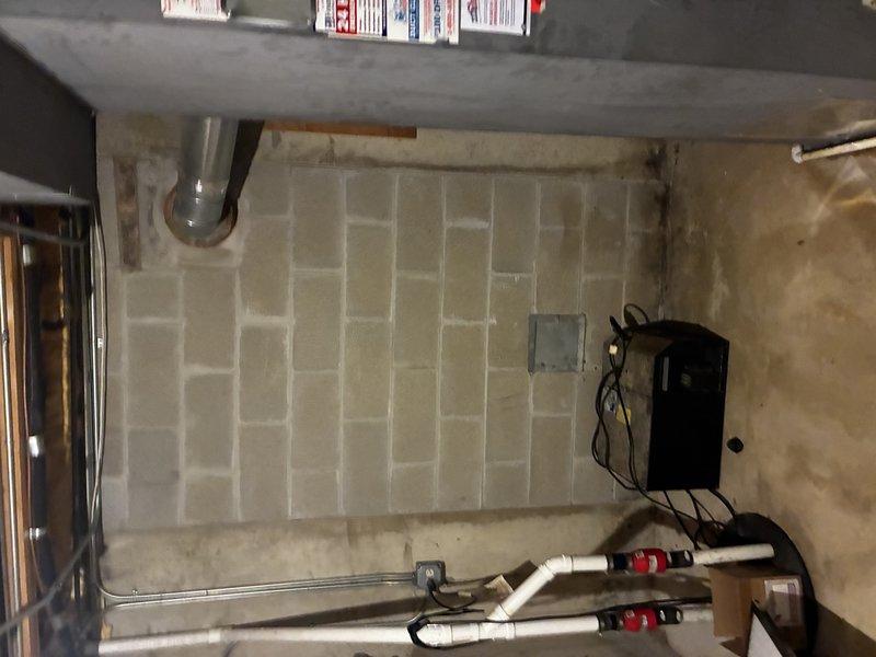 Conducted comprehensive site evaluation for tankless water heater conversion at residential property. Assessed existing tank-style water heater installation showing significant age-related deterioration with visible rust staining on exterior surface. Documented current plumbing configuration including copper supply lines, brass shutoff valves, white PVC discharge piping, and expansion tank. Evaluated utility room infrastructure including concrete block walls, available clearances, existing electrical service, gas connections, and ventilation requirements. Provided detailed estimate for complete removal of conventional storage tank unit and installation of new tankless water heating system with necessary upgrades to meet current code requirements.