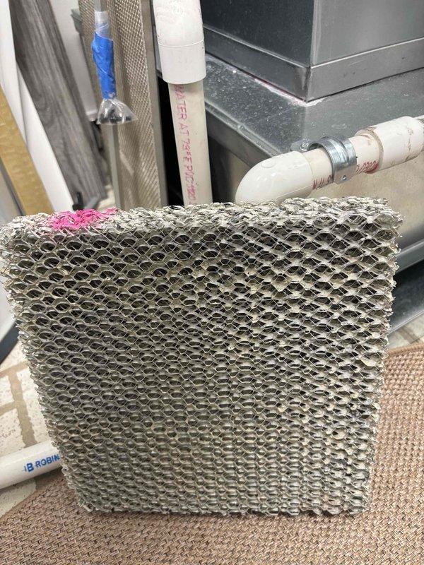 Completed seasonal maintenance agreement service on HVAC system including fan coil unit, heat strip, and humidifier. Inspected humidifier evaporator pad which showed heavy mineral deposits and scale buildup throughout honeycomb mesh structure, indicating extended use in hard water conditions. Evaluated control board and electrical connections, verifying proper wiring and component operation. Installed 16x20x1 filter as part of routine maintenance protocol.
