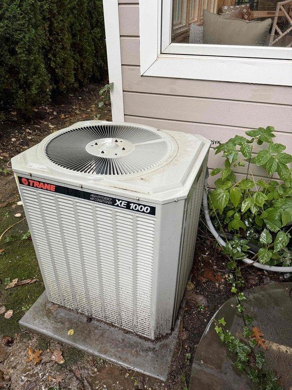 Responded to indoor air quality concern regarding high humidity levels remaining above 81 percent in residence with approximately 30-year-old Trane XE 1000 cooling system. Performed diagnostic assessment of outdoor condensing unit and documented equipment condition with photos showing weathered but operational unit positioned on concrete pad with visible dirt accumulation on cabinet panels. Given the age of the system and persistent humidity control issues, recommended evaluation of dehumidification capacity and potential system upgrades to address IAQ concerns effectively.