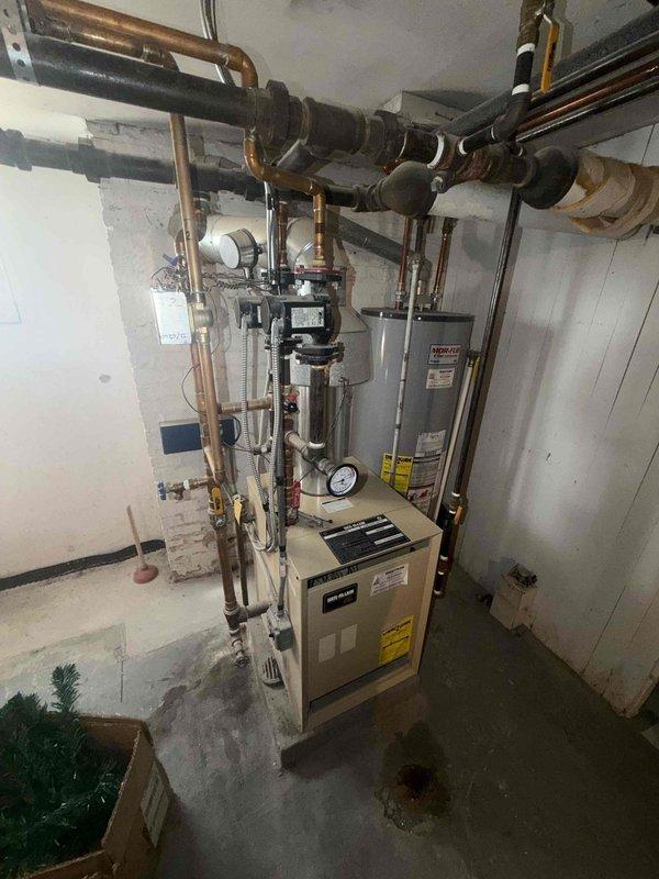Completed comprehensive maintenance inspection on residential boiler system as part of scheduled agreement service. Verified proper operation of all heating components, inspected copper piping connections, pressure gauge readings, and safety controls. Documented system condition with photos showing boiler unit, water heater, circulation pump, and associated plumbing infrastructure all functioning within normal parameters.