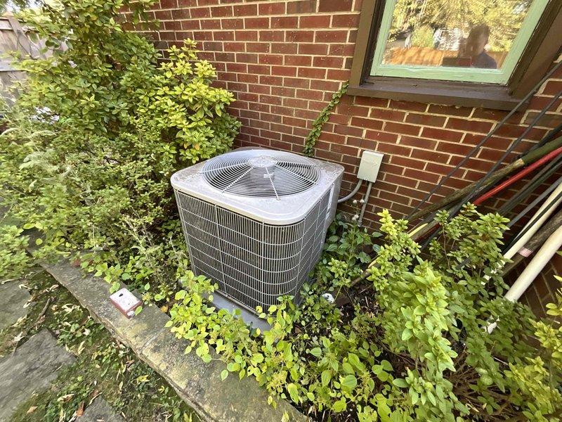Conducted on-site evaluation of existing 15-year-old air conditioning system for replacement estimate. Inspected outdoor condenser unit positioned on concrete pad against exterior brick wall, noting weathered equipment and overgrown vegetation requiring clearance. Assessed indoor HVAC components in mechanical room, including furnace unit and existing ductwork configuration with PVC piping system. Documented current system specifications and spatial requirements, photographed equipment and installation areas, and provided comprehensive replacement options for new cooling system to meet anticipated 2026 replacement timeline.