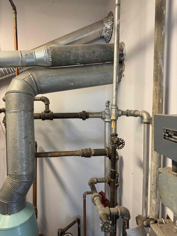 Performed an on-site assessment for replacement of an existing A.O. Smith copper-tube boiler, with easy access to the mechanical area. Documented the existing equipment, flue/vent piping, and mixed galvanized, black iron, and copper supply/return piping, including isolation valves, unions, and circulator components, and took clearance measurements to verify fit for the new unit. Piping and flue showed minor surface wear and discoloration but no significant corrosion, and the estimate was prepared for the boiler replacement.