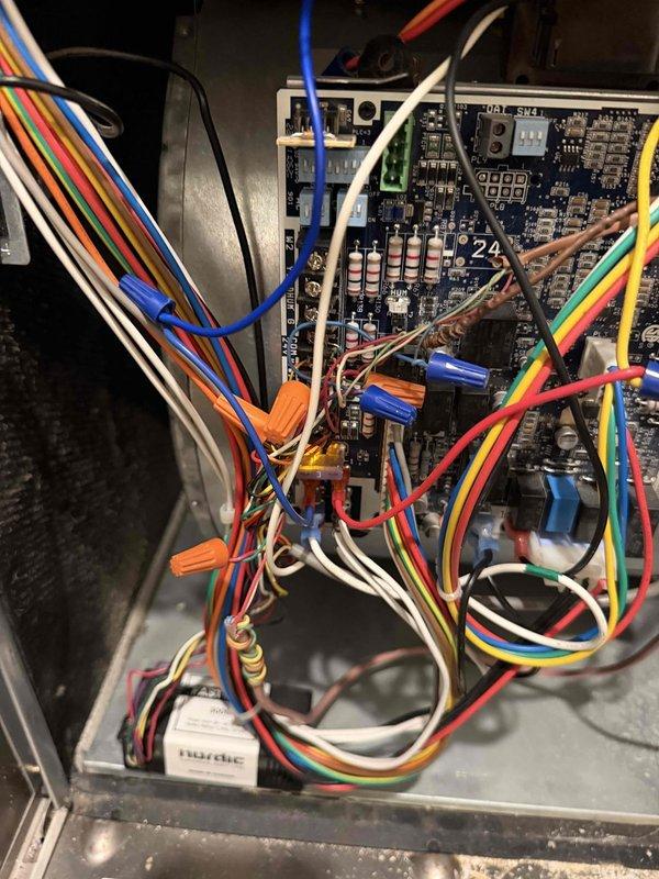 Responded to a no-cool call where the indoor blower operated but the outdoor condensing unit failed to energize following a recent blower motor and wheel replacement. Inspected the air handler control board and low-voltage wiring, which was found dense and disorganized with loosely draped and tangled conductors, and verified the thermostat control circuit and 24V signal path to the condenser contactor. Checked the refrigerant-side components, including the valve and brass fitting connections, and measured line temperature to confirm system operation and restore cooling.