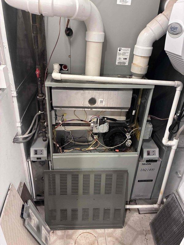 Responded to a no-heat complaint (furnace blowing cold air) and inspected the gas furnace with the lower access panel removed, finding standing water and rust/mineral staining on the base pan around the PVC flue/condensate connection, indicating a condensate drainage leak. Inspected the condensate drain line, collar, and fittings serving the furnace and associated coil cabinet, and addressed the water intrusion at the source to restore proper drainage and safe operation; tested the unit to verify heat output.