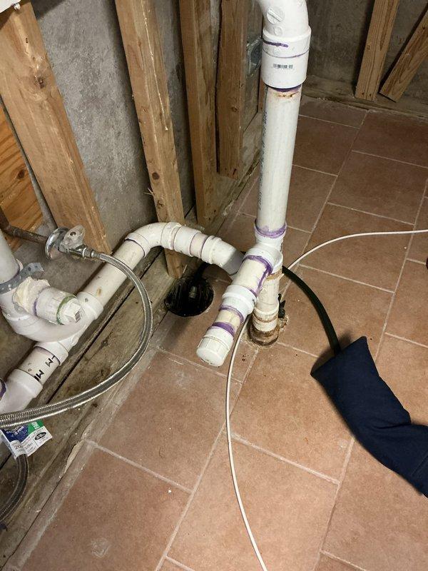 Inspected the laundry area drain and supply plumbing to locate the reported leak and identified staining at the base of the PVC drain assembly where it meets the floor drain. Repaired the PVC drain connections, including primed and cemented joints and fittings, and verified the braided stainless steel supply lines and shutoff valves were secure and leak-free. Tested the system under normal operation to confirm the leak was resolved.